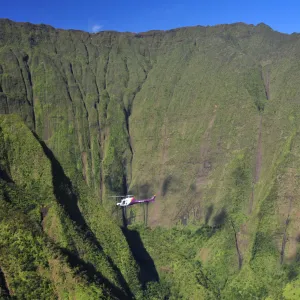 a helicopter with tall lush green mountains in the background