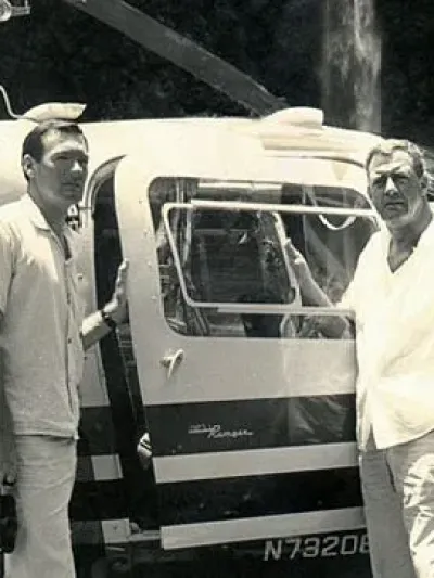 black and white photo of two men next to a helicopter