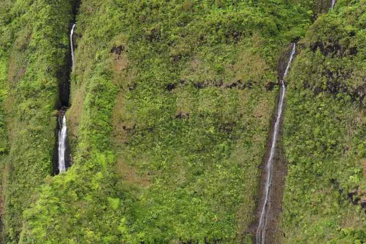 Lush green cliffs with small waterfalls cascading down the rocky surfaces.