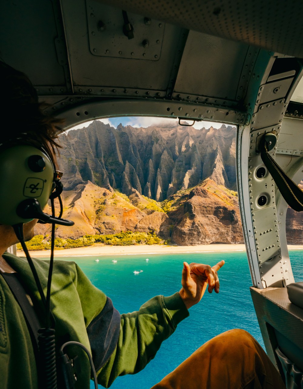 Person in helicopter above scenic coastline with cliffs and ocean.